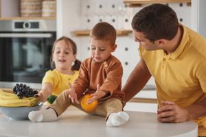Ein Vater begleitet zwei Kinder an der Küchentheke
