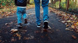 Zwei Menschen gehen gemeinsam einen herbstlichen Weg entlang